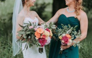 Bride and Maid of Honor hugging on summer wedding day